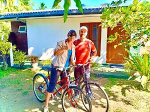 ポロンナルワにあるARANI HOMESTAYの家の前で自転車の横に立っている二人