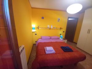a small bedroom with a red bed in a yellow room at La casa dei sentieri in Rovetta