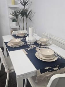 een witte tafel met borden en wijnglazen erop bij Nariken Apartments, Cardiff in Cardiff