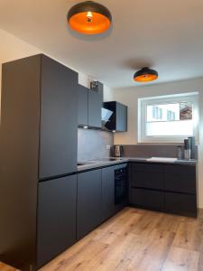 a large kitchen with black cabinets and a window at Ferienwohnung mit Terrasse und Garten mit Blick auf das Karwendelgebirge in Mittenwald +5 photos