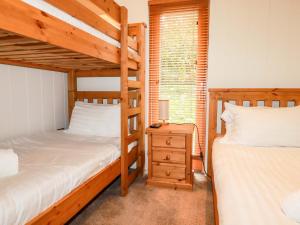 a bedroom with two bunk beds and a night stand at 1 Hedgerows in Looe