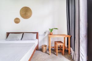 a small bedroom with a bed and a table at Drifter - Rooms & Food in Midigama
