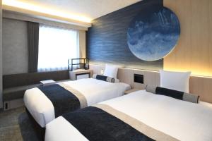 two beds in a hotel room with a painting on the wall at HOTEL MYSTAYS Ochanomizu Conference Center in Tokyo