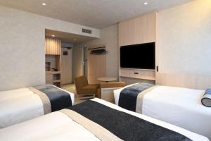 a hotel room with two beds and a flat screen tv at HOTEL MYSTAYS Ochanomizu Conference Center in Tokyo