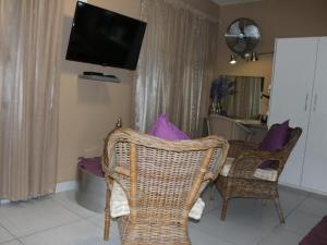 a living room with wicker chairs and a flat screen tv at An Exclusive Guesthouse too in Nelspruit +11 photos