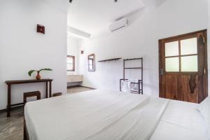 a white bedroom with a large bed and a window at Drifter - Rooms & Food in Midigama