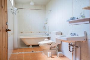 a bathroom with a tub and a toilet and a sink at FamA in Nakafurano