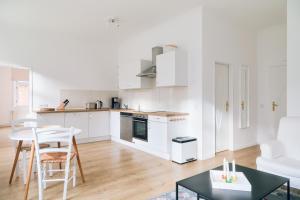a kitchen with white cabinets and a table and chairs at Gartenappartment in Barkelsby