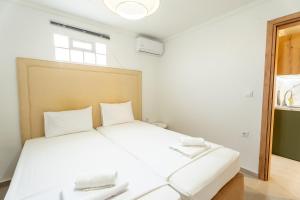 a bedroom with a white bed with two phones on it at Oasis Apartments Maggana Xanthi in Xanthi