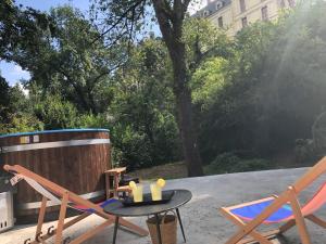 eine Terrasse mit 2 Stühlen, einem Tisch und einer Badewanne in der Unterkunft Le Dort'Thouars - bord de rivière et bain nordique in Thouars