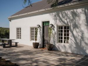 Casa blanca con mesa de picnic y patio en Melkhout Farm Cottage, en Bonnievale
