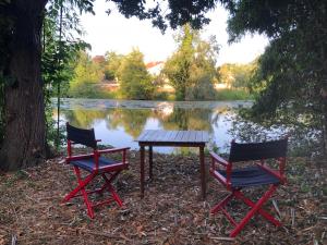 zwei Stühle und ein Picknicktisch vor einem See in der Unterkunft Le Dort'Thouars - bord de rivière et bain nordique in Thouars + 5 Fotos