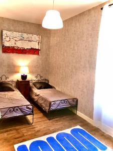 1 Schlafzimmer mit 2 Betten und einem blauen Teppich in der Unterkunft Le Dort'Thouars - bord de rivière et bain nordique in Thouars