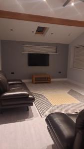 a living room with leather furniture and a flat screen tv at Stylish house in Roydon in Roydon