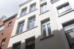 un edificio blanco con ventanas junto a un edificio de ladrillo en Stadsstudio op toplocatie, en Amberes