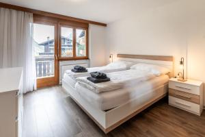 a bedroom with a large white bed and a window at Fabi`s Horu Lodge in Zermatt