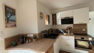 a kitchen with white cabinets and a wooden counter top at Gite La Brise des Bois in Andernos-les-Bains