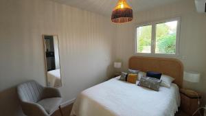 a bedroom with a bed and a chair and a mirror at Gite La Brise des Bois in Andernos-les-Bains