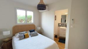 a bedroom with a white bed with pillows and a window at Gite La Brise des Bois in Andernos-les-Bains +20 photos