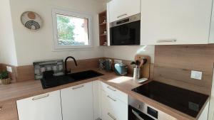 a kitchen with white cabinets and a sink and a microwave at Gite La Brise des Bois in Andernos-les-Bains