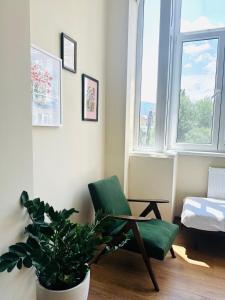 a green chair and a plant in a room with a window at Feel at home chugureti in Tbilisi City
