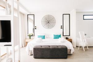 a white bedroom with a bed and a large clock on the wall at Hotel Almirante in Alicante