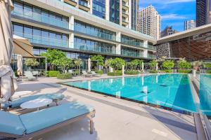 ein Swimmingpool mit zwei Liegestühlen vor einem Gebäude in der Unterkunft FIRST CLASS 1BR Charming City View in Dubai