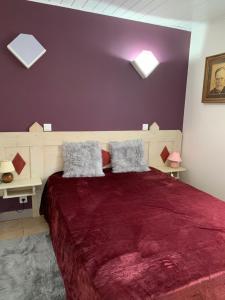 a bedroom with a large red bed with two pillows at Chalet Les Ammonites 2 chambres en Franche Comte au calme dans la nature in Nans-sous-Sainte-Anne