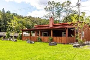 a house with a yard with rocks in front of it at Mountain Cabin with Scenic Views and Hot Tub in Windham