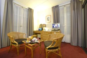 ein Zimmer mit zwei Stühlen, einem Tisch und einem Schreibtisch in der Unterkunft Hôtel d’Angleterre Grenoble Hyper-Centre in Grenoble