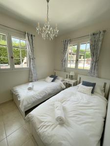 2 letti in una camera con finestre e lampadario a braccio di VILLA LA LOUBIANE VI4428 By Riviera Holiday Homes a Vence Altre 24 foto