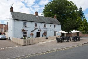 a white building with tables and umbrellas on a street at Green Dragon, Welton by Marston's Inns in South Cave