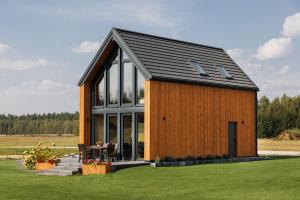 a large wooden house with a black roof at Szept Oberlandu - boutique, luxury Villa in Liva Park in Liwa