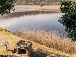 a brick oven next to a body of water at Riverside Self Catering Cabin in Wilderness +12 photos