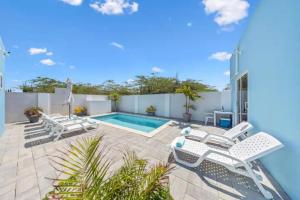 a patio with chairs and a swimming pool at Apricity Suites Aruba in Noord