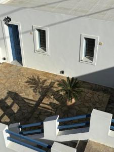 a white building with white chairs and a plant at Andros Guesthouses in Andros