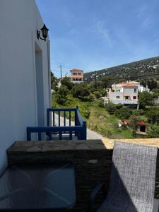 a blue bench and a chair on a balcony at Andros Guesthouses in Andros