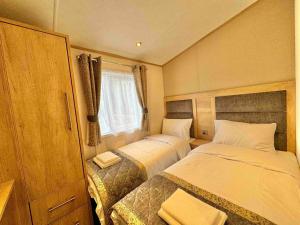 Un dormitorio pequeño con dos camas y una ventana. en Glenmoor Lodge, en Clitheroe