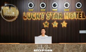 波来古市LuckyStar Hotel的站在一张桌子后面的手提电脑的女人