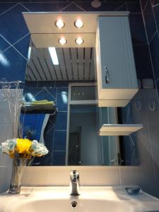 een badkamerwastafel met spiegel en een vaas met bloemen bij Accommodation JT Old Town Historical sites in Ohrid