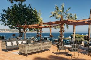 a patio with chairs and umbrellas and the ocean at Hotel de Mar Gran Meliá - Adults Only - The Leading Hotels of the World in Illetas