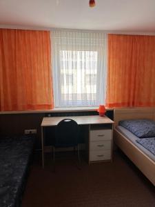 a bedroom with a desk and a bed and a window at Pension Glückauf in Sondershausen