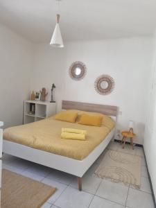 a white bedroom with a bed with yellow pillows at Appartement coquet Le Boulou in Le Boulou