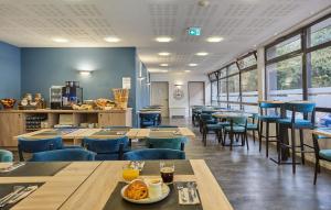 a restaurant with wooden tables and blue chairs at Résidence Odalys Archipel in La Rochelle