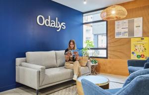a woman sitting on a couch in a waiting room at Résidence Odalys Archipel in La Rochelle