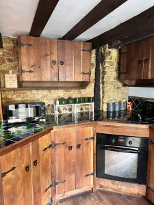 a kitchen with wooden cabinets and a stove top oven at Quay Cottage in Sandwich, UK in Sandwich