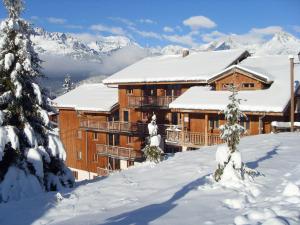un gran edificio cubierto de nieve con montañas en el fondo en Appartement Modane 4 pièces, idéal ski, 6-8 pers, 65m², proche télécabine et commerces - FR-1-265-66, en Valfréjus