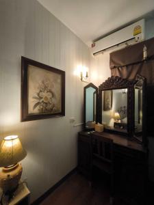 une chambre avec un miroir et une lampe sur une commode dans l'établissement Bann Chana BKK, à Bangkok