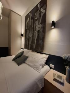 a bedroom with a white bed with a painting on the wall at Casa Nice - centro Bogliasco in Bogliasco