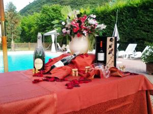 een tafel met een vaas met bloemen en een fles wijn bij Case Vacanza Fiocchi in Arrone